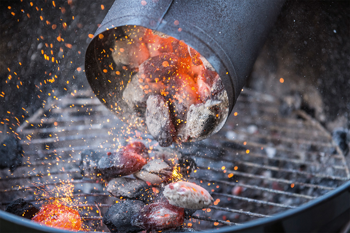 Gloeiende barbecuekolen worden met een brikettenstarter in een barbecue gegoten