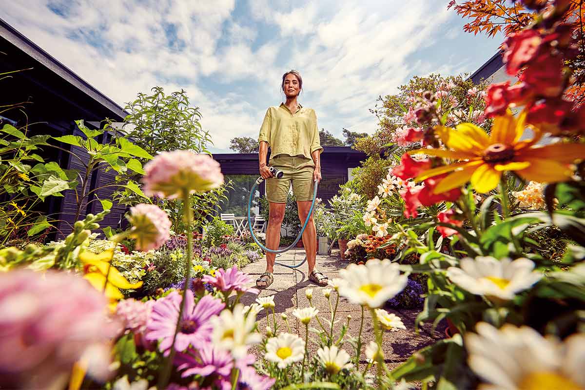 Vrouw houdt tuinslang vast in bloeiende tuin