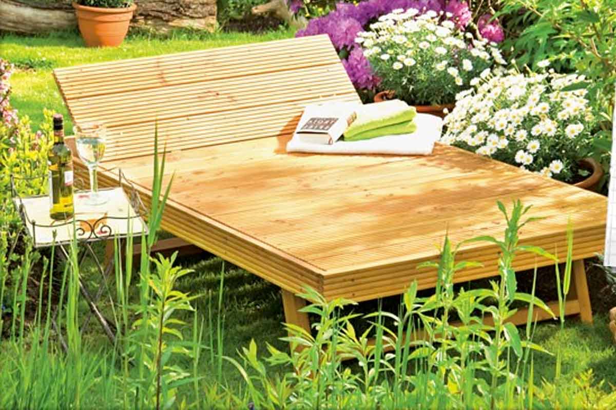 Houten ligbed in de tuin met bijzettafel, drankje en planten