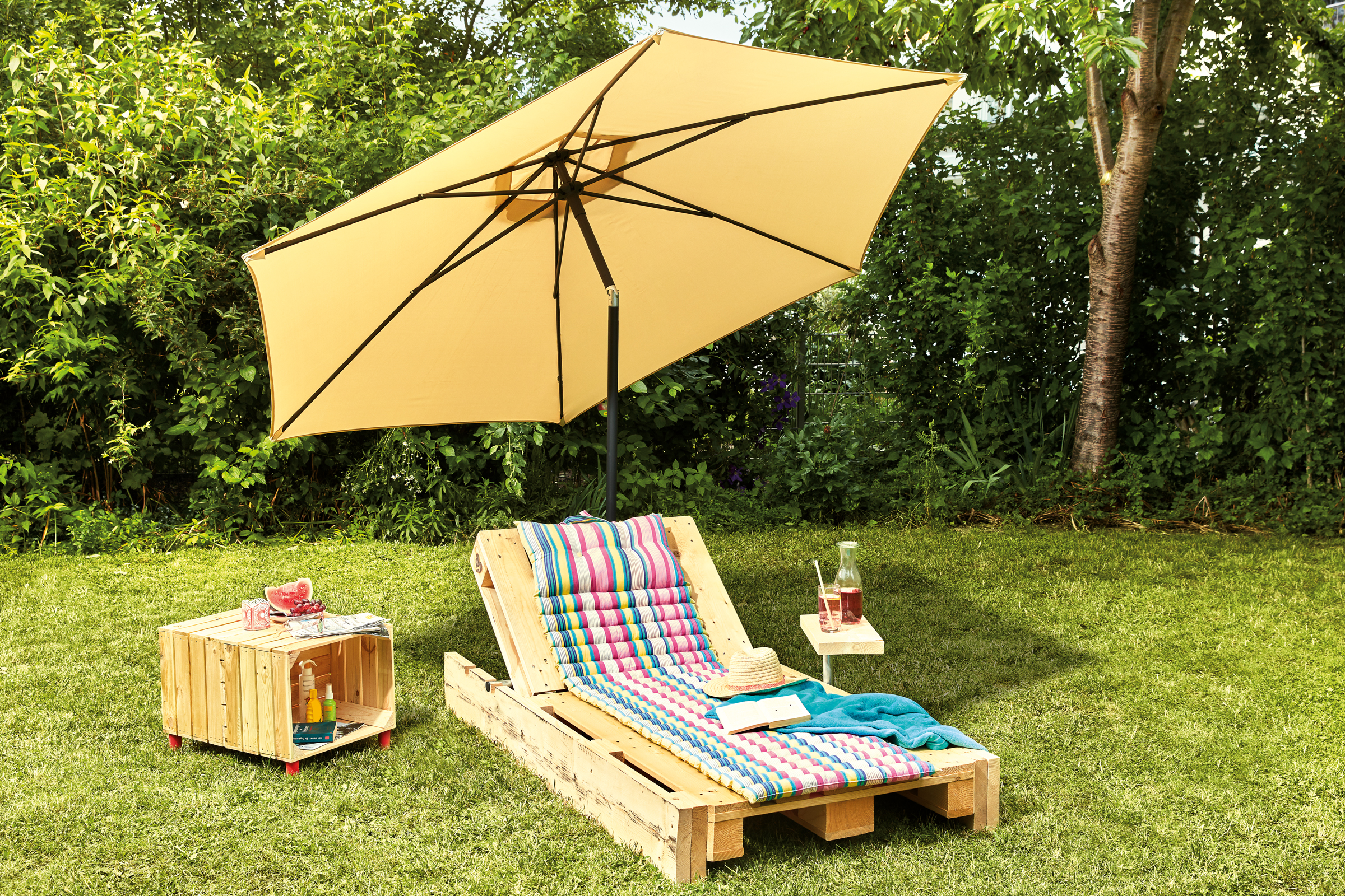 Tuinscene met parasol, ligstoel van houten pallet en bijzettafel