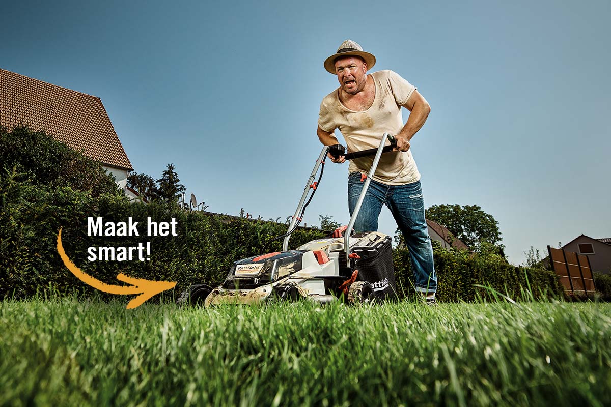 Een man maait het gazon met een grasmaaier in de tuin.