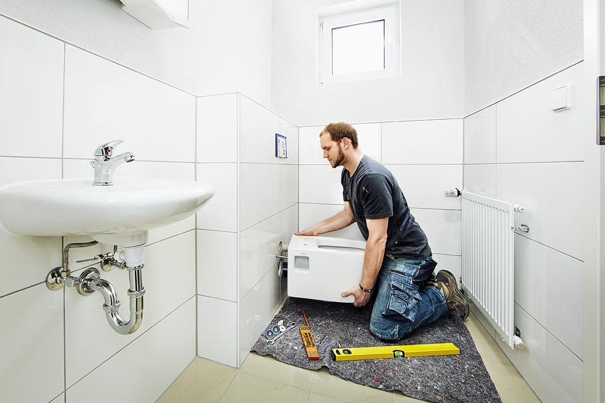 Installatie van een toilet in een badkamer met wastafel en radiator