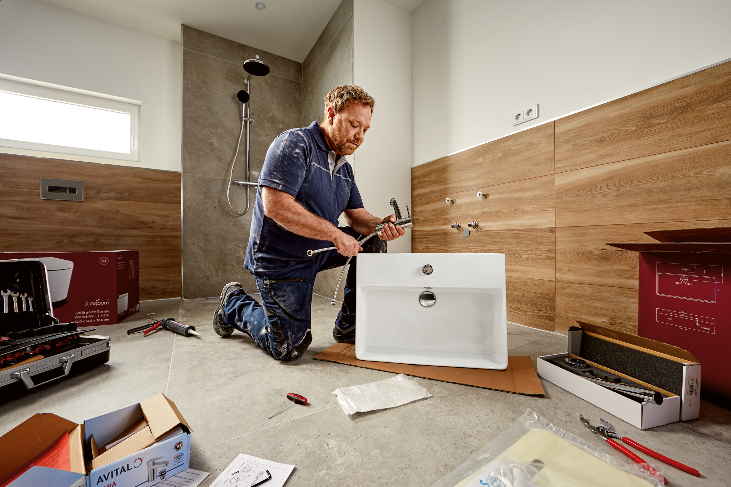 Installateur monteert wastafel in badkamer met gereedschap en armaturen