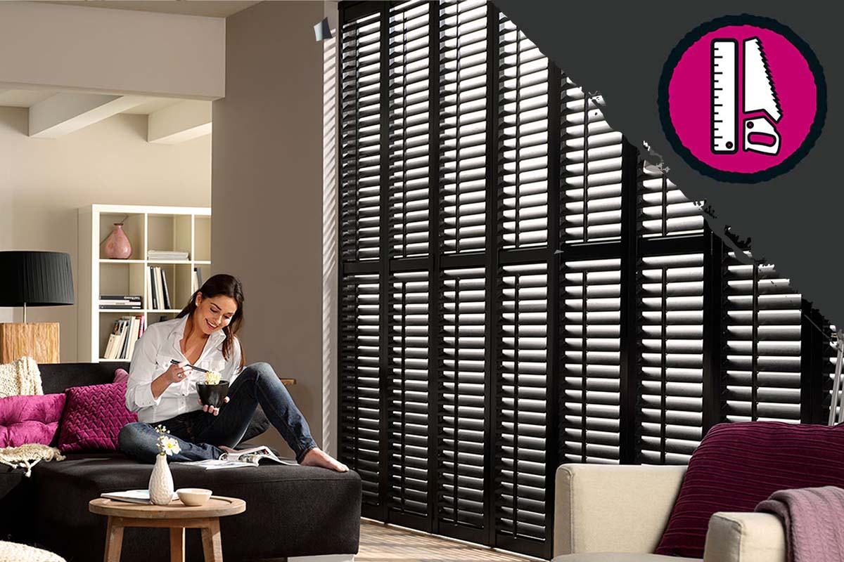 Woonkamer met houten jaloezieën en vrouw zittend op de bank