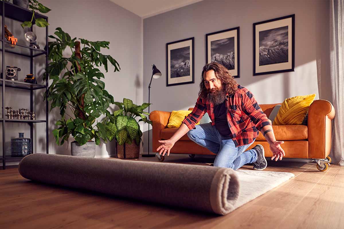 Man rolt tapijt uit in de woonkamer