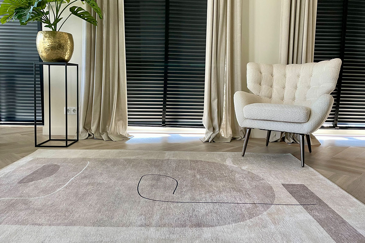 Woonkamer met vloerkleed, fauteuil, gordijnen en plant