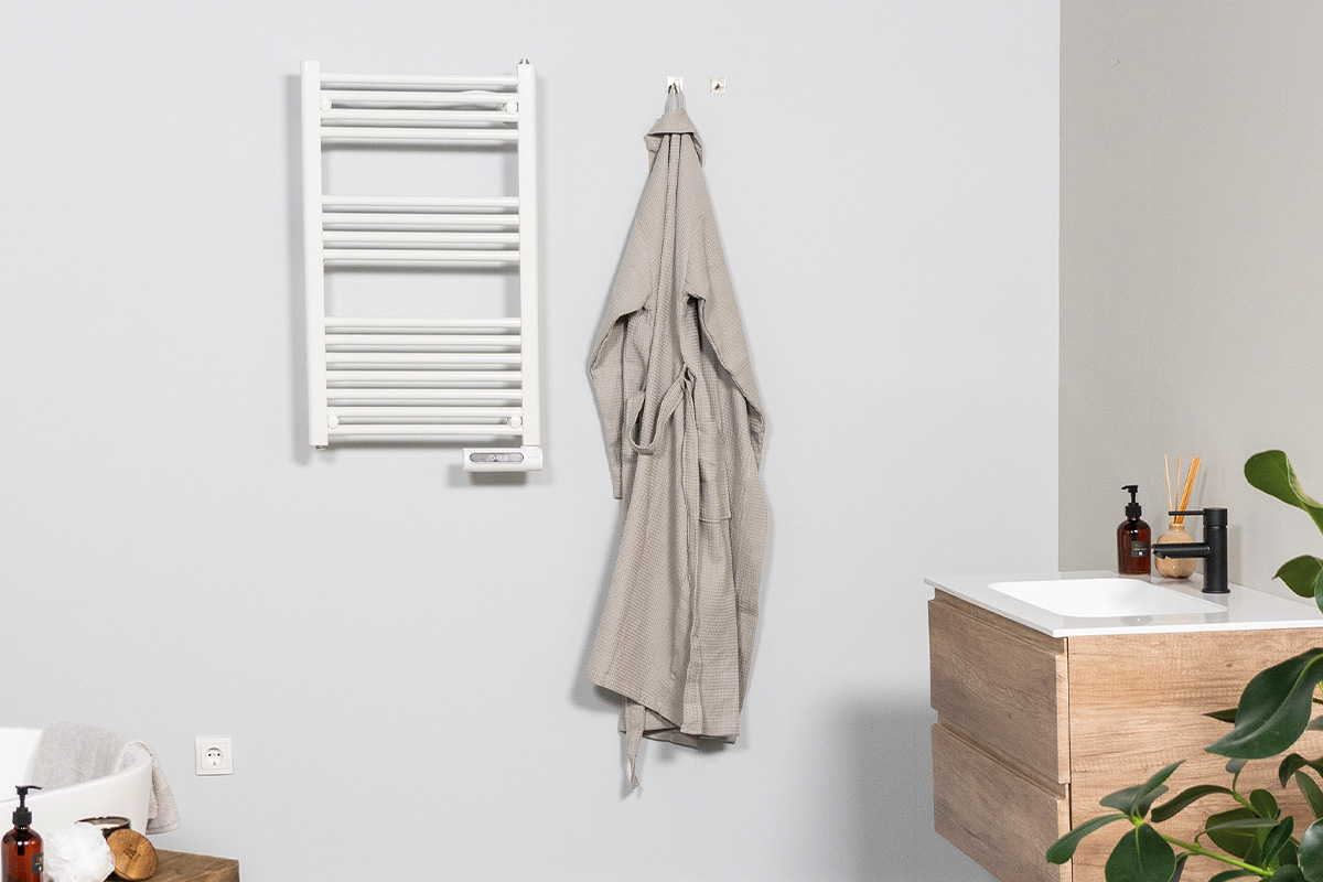 Badkamerzicht met handdoekradiator, badjas en wastafel