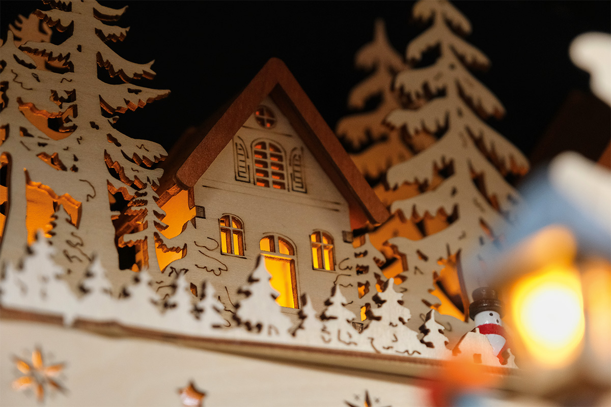 Houten kerstdecoratie met huis, bomen en sneeuwpop, verlicht
