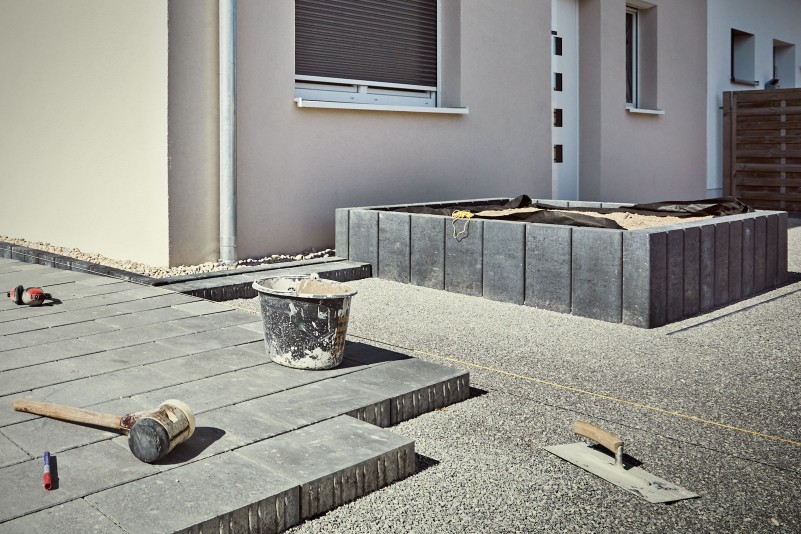 Buitenscène met bestrating, gereedschap en plantenbak
