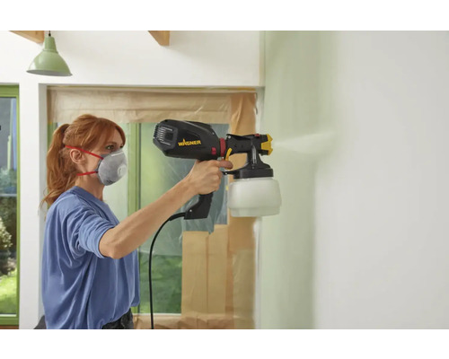 Vrouw schildert muur met Wagner verfspuitsysteem