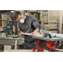 Een man zaagt een houten plank met een Einhell tafelzaag in een werkplaats.