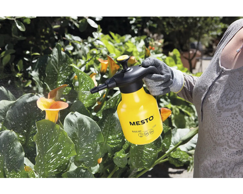 Een persoon gebruikt een gele Mesto drukspuit voor plantverzorging.