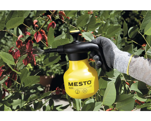 Tuinscène met een persoon die planten besproeit met een Mesto drukspuitfles.