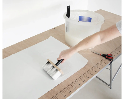 Lijm aanbrengen op een behang met een kwast