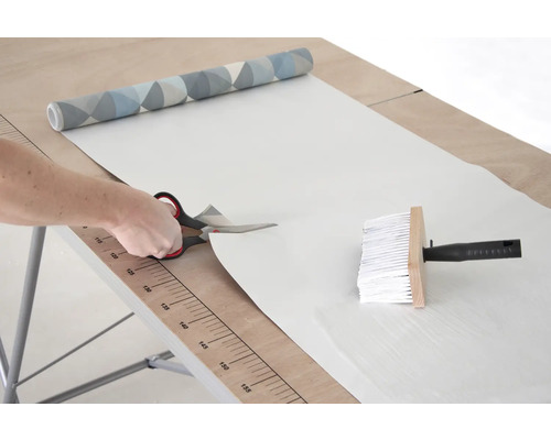 Behang knippen met een schaar op een behangtafel