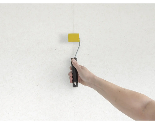 Hand schildert muur met verfroller geel