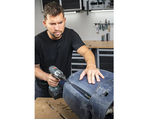 Een man gebruikt een accuschroevendraaier voor reparatiewerkzaamheden aan een onderdeel.