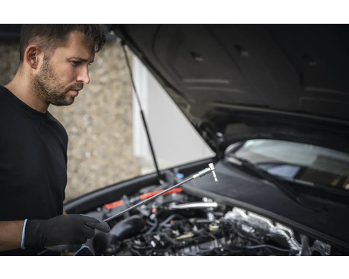 Man met dopsleutel en geopende motorkap van een auto
