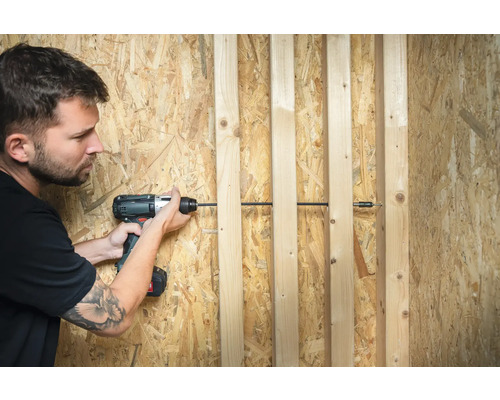 Man schroeft houten latten op een spaanplaat met een accuschroevendraaier