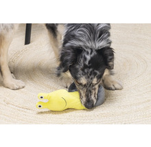 Een hond speelt met een geel slakkenhondenspeeltje op een tapijt.