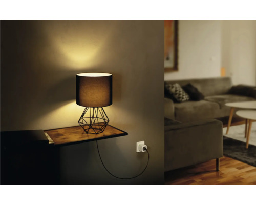 Decoratieve tafellamp met geometrisch frame en stoffen kap op een plank