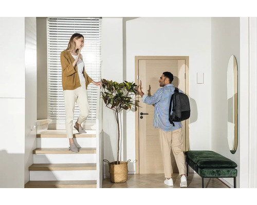 Lichte hal met trap, kapstok en twee mensen die afscheid nemen.