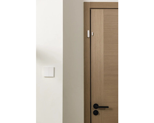 Een houten deurkozijn met een sensor en een lichtschakelaar