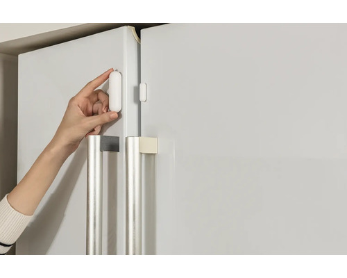 Installatie van een deur- en raamsensor op een koelkast.