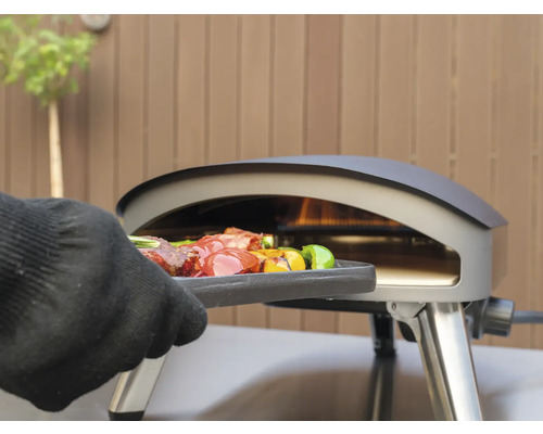 Een grilloven met gegrild voedsel wordt met een handschoen bediend.