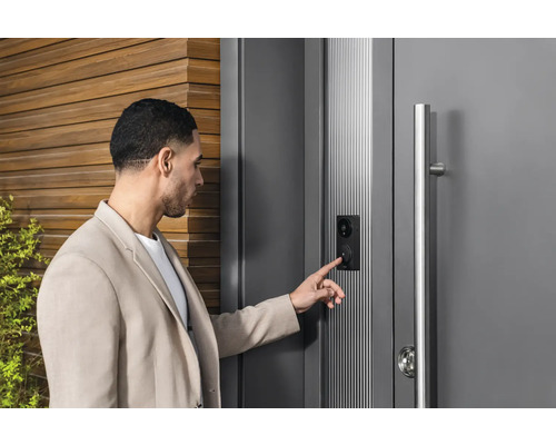 Man bedient een moderne voordeur met intercomsysteem en camera