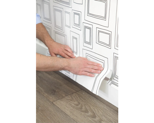 Aanbrengen van wit behang met framepatroon op een muur