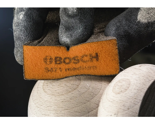 Bosch schuurpad wordt vastgehouden door een hand met beschermende handschoen