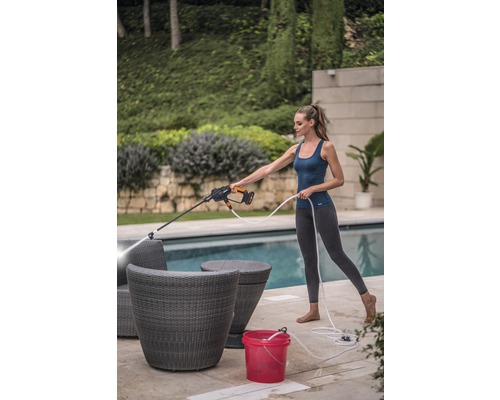 Vrouw reinigt tuinmeubilair met een hogedrukreiniger buitenshuis.