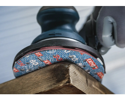 Detailopname van een schuurmachine die een stuk hout bewerkt.