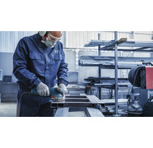 Een arbeider schuurt een metalen stuk met een schuurmachine.