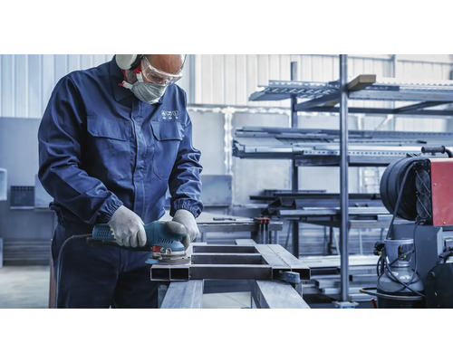 Een vakman schuurt metaal met een schuurmachine in een werkplaats.