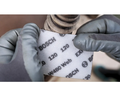 Iemand schuurt een werkstuk met een schuurpad met korrel 120 van Bosch.