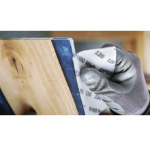 Een persoon schuurt een werkstuk met schuurpapier korrel 120.