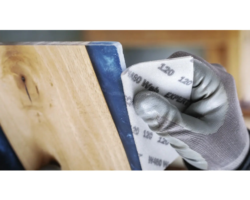 Een persoon schuurt een werkstuk met schuurpapier korrel 120.