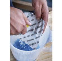 Persoon snijdt Bosch schuurpapier met korrel 180 in een maatbeker