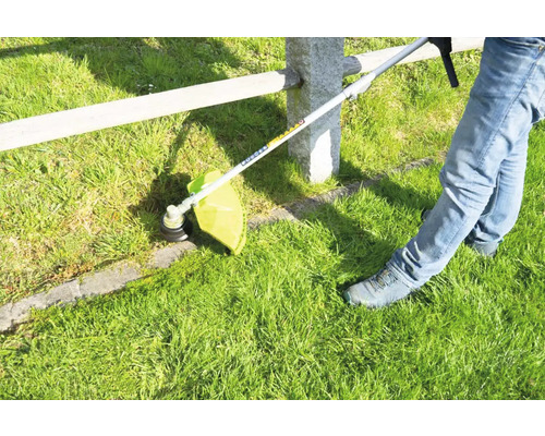 Gras trimmer in gebruik voor het maaien van gras langs een hek.