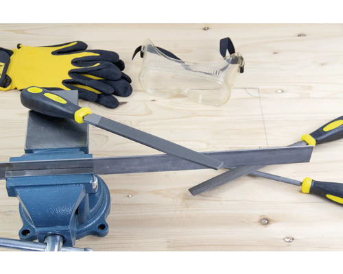 Werkbank met bankschroef, metalen vijlen, veiligheidsbril en werkhandschoenen