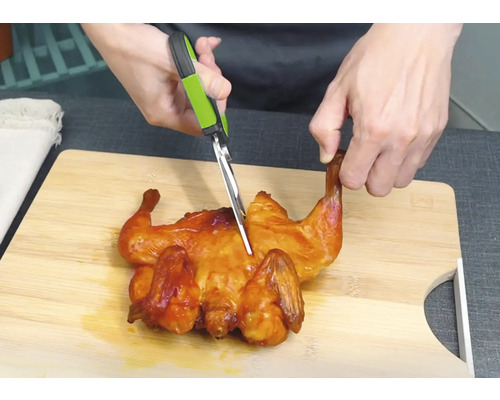 Kip wordt met een keukenschaar op een snijplank gesneden.