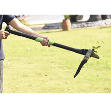 Persoon gebruikt een onkruidsteker om onkruid te verwijderen in de tuin.