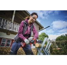 Vrouw zaagt een stuk hout met een draadloze kettingzaag op een zaagbok