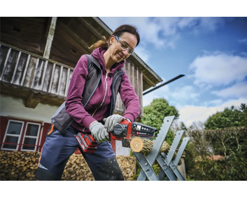 Vrouw zaagt een stuk hout met een draadloze kettingzaag op een zaagbok