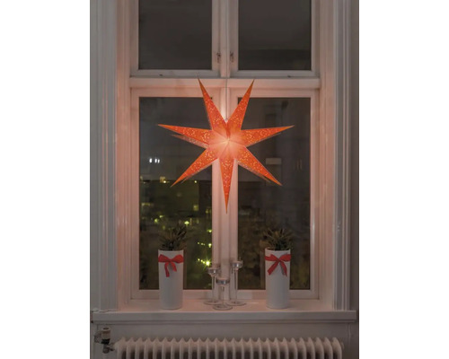 Decoratief raam met verlichte papieren ster, potplanten en kandelaars