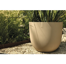 Beige kunststof bloempot met Elho logo en golvende textuur in de tuin.