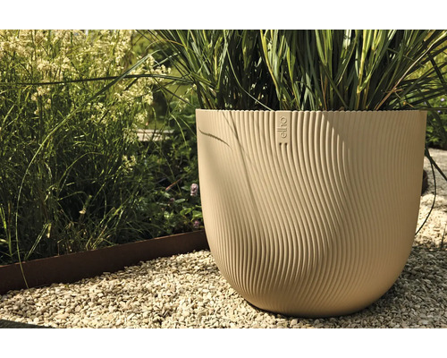 Beige bloempot met planten en Elho logo in de tuin.
