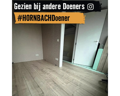 Een lichte kamer met laminaatvloer en behang met motief.